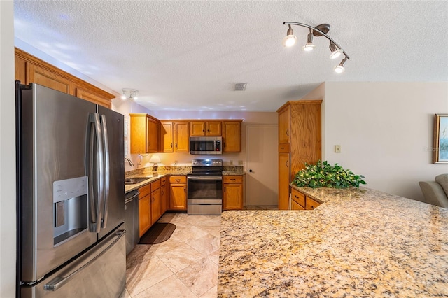 kitchen with kitchen peninsula, sink, a textured ceiling, and appliances with stainless steel finishes