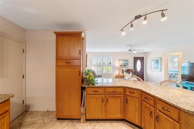 kitchen featuring ceiling fan, light tile patterned floors, light stone countertops, and a textured ceiling