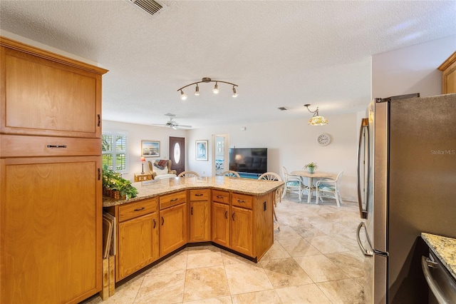 kitchen with kitchen peninsula, ceiling fan, stainless steel appliances, and a textured ceiling