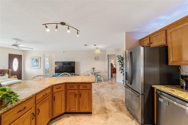 kitchen with light stone countertops, appliances with stainless steel finishes, a textured ceiling, and ceiling fan