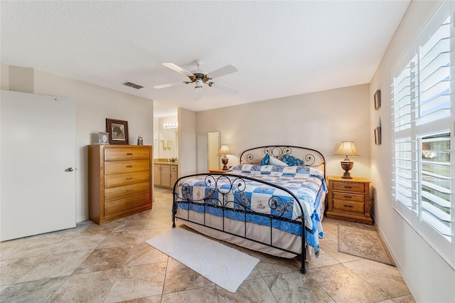 bedroom with a textured ceiling, ensuite bath, and ceiling fan