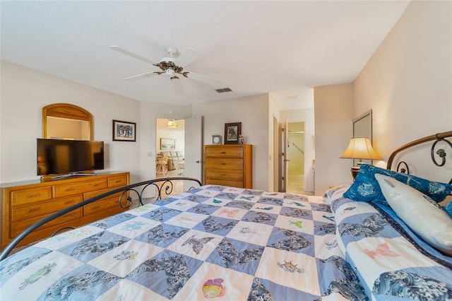 bedroom featuring ceiling fan, ensuite bathroom, and a textured ceiling