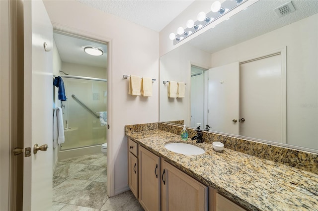 bathroom featuring vanity, a textured ceiling, toilet, and walk in shower