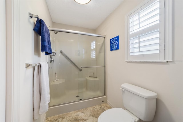 bathroom featuring toilet, an enclosed shower, and a textured ceiling