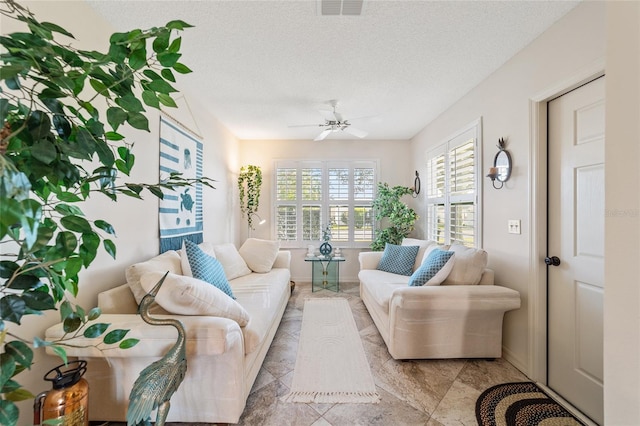 living room featuring ceiling fan and a textured ceiling