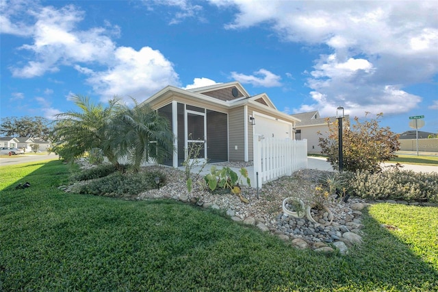 view of property exterior with a yard, a garage, and a sunroom