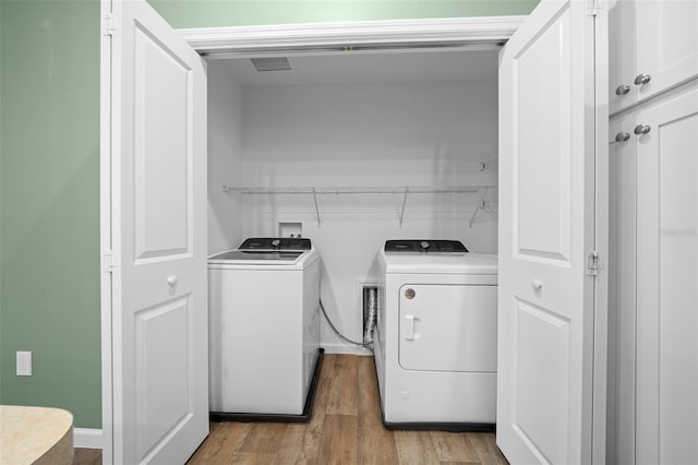 laundry area featuring washer and dryer and light hardwood / wood-style floors