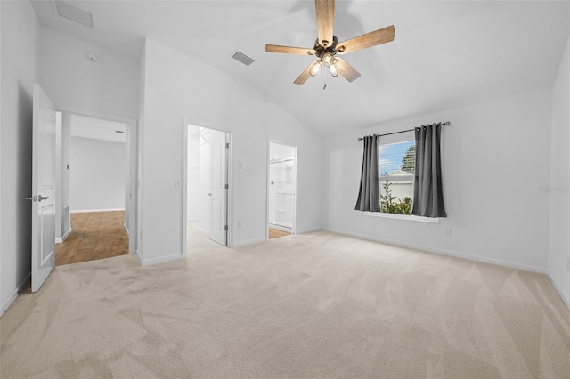 unfurnished bedroom with ceiling fan, light colored carpet, lofted ceiling, and ensuite bath