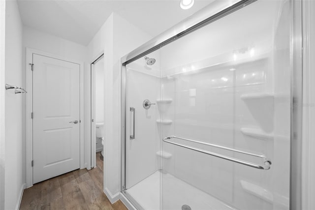 bathroom featuring hardwood / wood-style flooring, toilet, and a shower with door