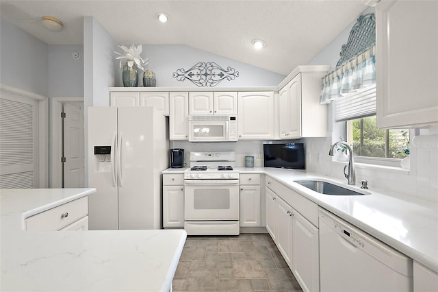 kitchen featuring white cabinetry, white appliances, sink, and vaulted ceiling