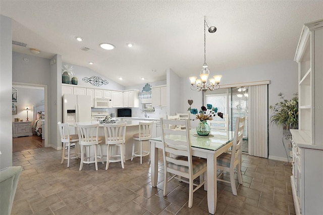 dining space featuring a textured ceiling, lofted ceiling, and a notable chandelier