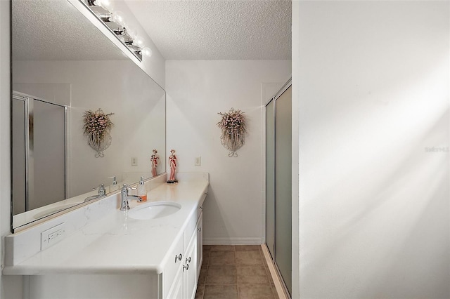 bathroom with a textured ceiling, vanity, tile patterned floors, and a shower with shower door