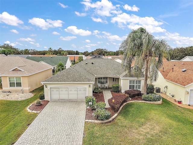 ranch-style home featuring a front yard, a garage, and central AC unit