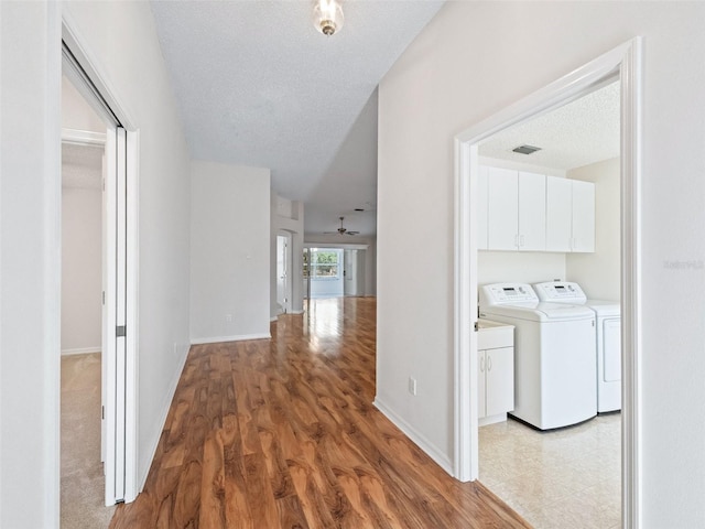 hall featuring light hardwood / wood-style flooring, washer and dryer, and a textured ceiling