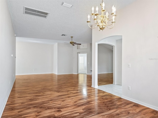 spare room with hardwood / wood-style flooring, ceiling fan with notable chandelier, a towering ceiling, and a textured ceiling