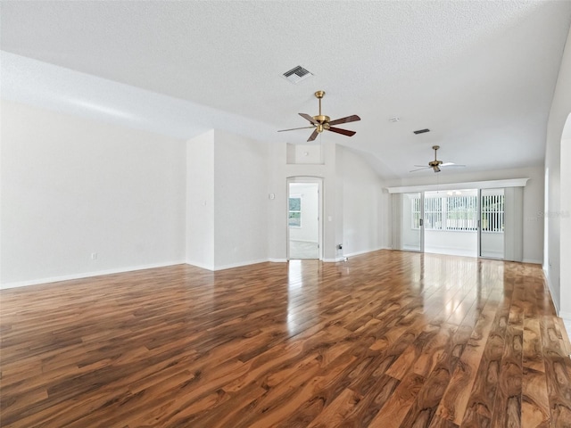 unfurnished living room with a textured ceiling, vaulted ceiling, ceiling fan, and dark wood-type flooring