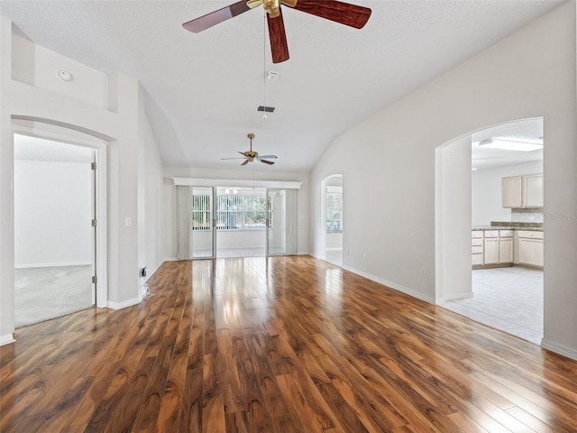 unfurnished living room with a textured ceiling, hardwood / wood-style flooring, and lofted ceiling