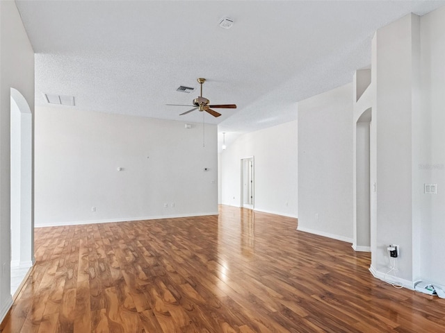 empty room with hardwood / wood-style floors, ceiling fan, lofted ceiling, and a textured ceiling