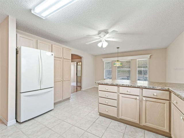 kitchen with light brown cabinets, white refrigerator, ceiling fan, a textured ceiling, and decorative light fixtures