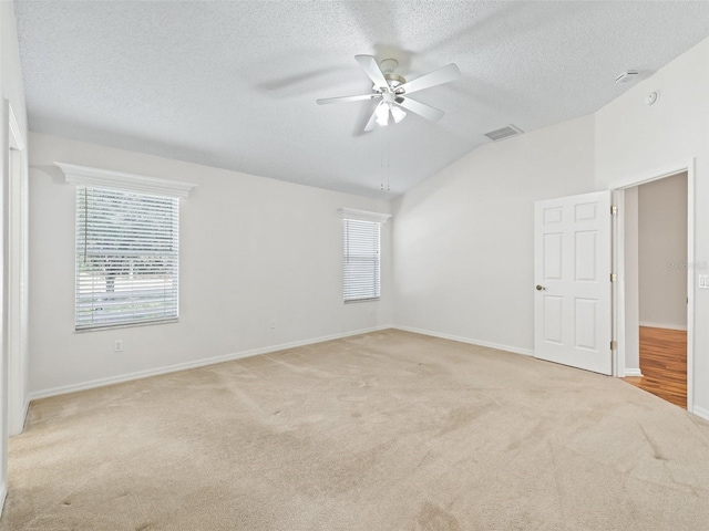 unfurnished room featuring ceiling fan, light colored carpet, lofted ceiling, and a textured ceiling