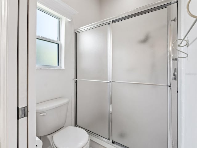 bathroom with a shower with door and toilet