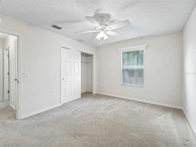 unfurnished bedroom featuring ceiling fan, a closet, and light colored carpet