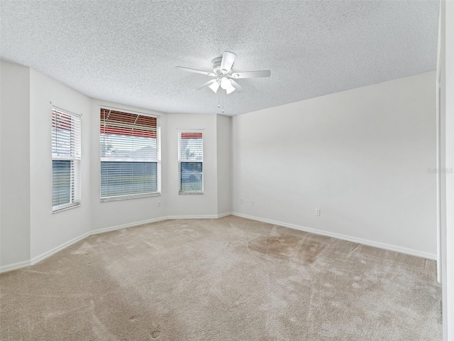 unfurnished room with plenty of natural light, light colored carpet, and a textured ceiling