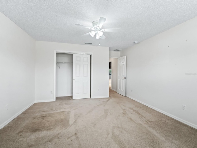 unfurnished bedroom with ceiling fan, a closet, light carpet, and a textured ceiling