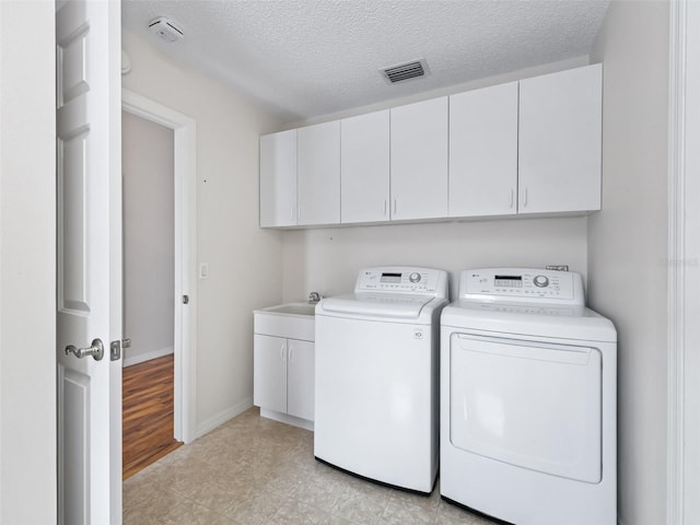 laundry area featuring cabinets, independent washer and dryer, and a textured ceiling