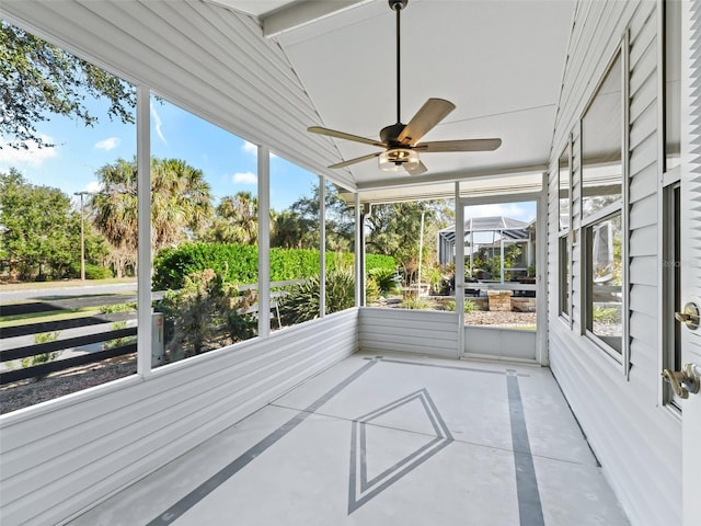 unfurnished sunroom featuring ceiling fan, a healthy amount of sunlight, and vaulted ceiling