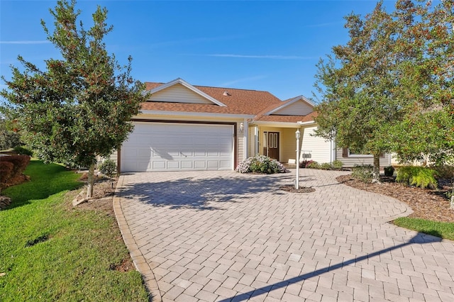 single story home with a garage, decorative driveway, and a front yard