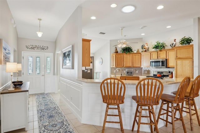 kitchen with lofted ceiling, visible vents, range, decorative backsplash, and stainless steel microwave