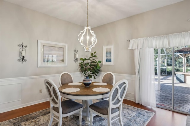 dining area featuring a wainscoted wall, an inviting chandelier, and wood finished floors