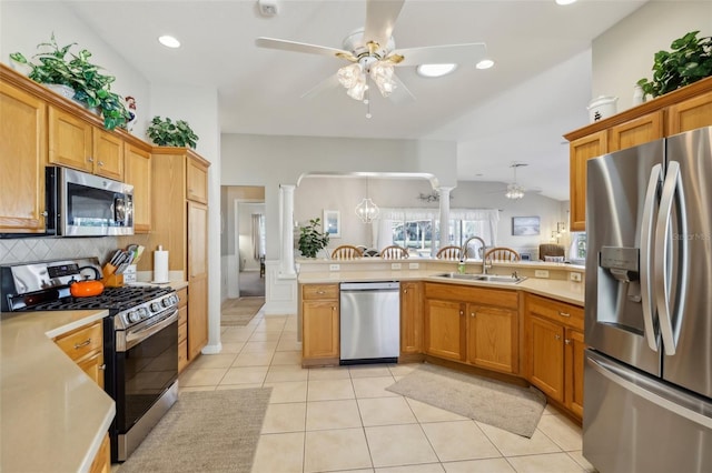 kitchen with kitchen peninsula, appliances with stainless steel finishes, backsplash, sink, and light tile patterned floors