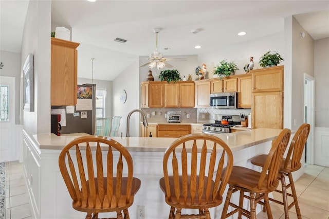 kitchen featuring stainless steel appliances, a peninsula, vaulted ceiling, light countertops, and decorative backsplash