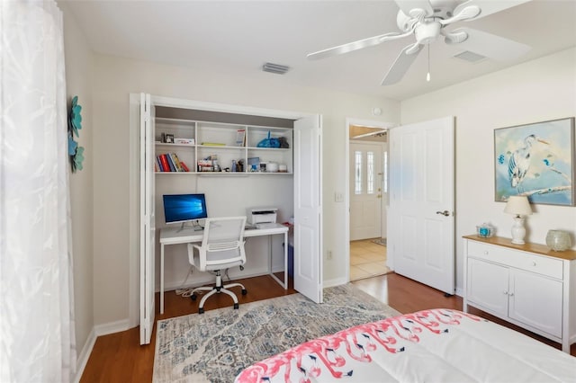 bedroom featuring baseboards, ceiling fan, visible vents, and wood finished floors