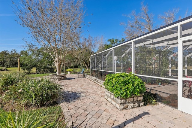 view of patio featuring glass enclosure and a fire pit