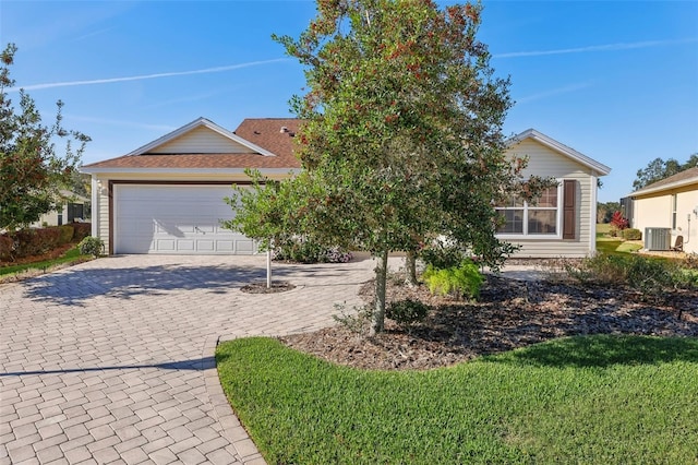 view of front of home with a garage, central AC unit, and decorative driveway