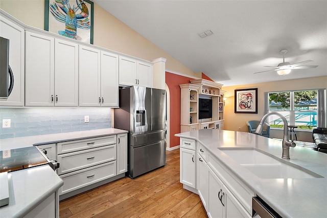 kitchen featuring lofted ceiling, white cabinets, sink, decorative backsplash, and appliances with stainless steel finishes