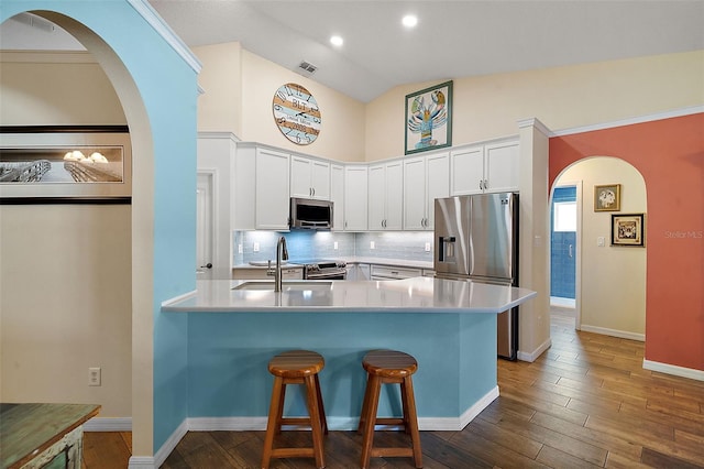 kitchen featuring sink, stainless steel appliances, backsplash, lofted ceiling, and white cabinets