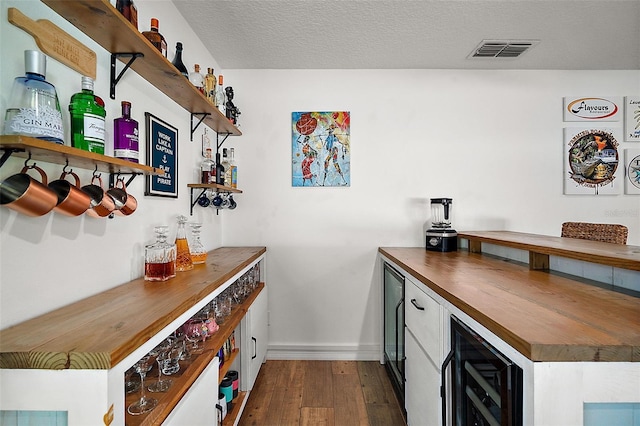 bar with butcher block countertops, wine cooler, dark wood-type flooring, and a textured ceiling