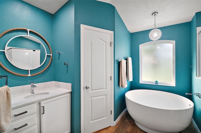 bathroom with a tub, vanity, wood-type flooring, and a textured ceiling