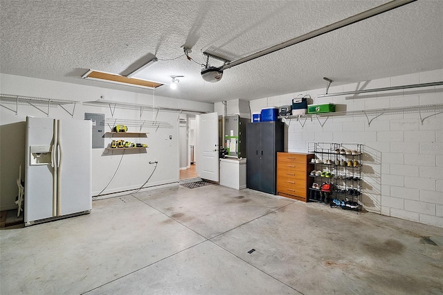 garage featuring electric panel, a garage door opener, and white fridge with ice dispenser