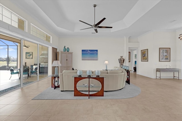 tiled living room featuring a raised ceiling, ceiling fan, and crown molding