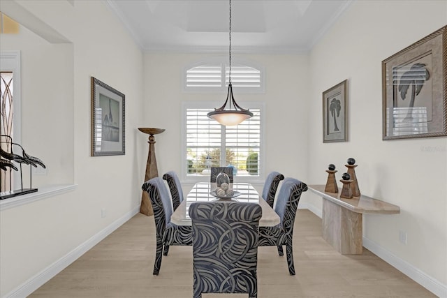 dining space featuring light wood-type flooring, a tray ceiling, and crown molding