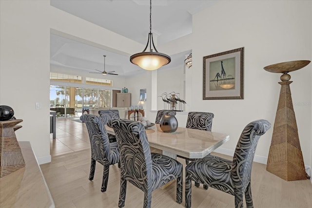 dining room featuring ceiling fan, a tray ceiling, and light hardwood / wood-style flooring