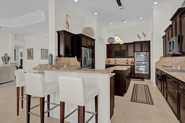 kitchen featuring kitchen peninsula, a kitchen breakfast bar, backsplash, light stone countertops, and stainless steel appliances