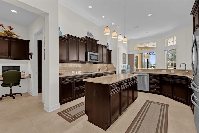 kitchen with backsplash, dark brown cabinetry, stainless steel appliances, pendant lighting, and a kitchen island