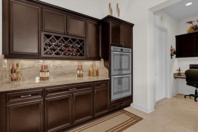 interior space featuring dark brown cabinets, light tile patterned floors, double oven, and tasteful backsplash