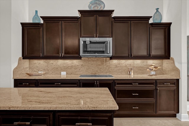 kitchen with tasteful backsplash, black electric cooktop, and dark brown cabinetry